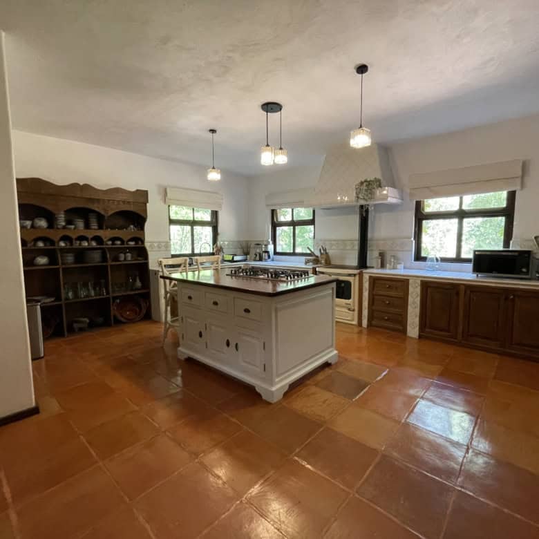 Spacious country kitchen with wooden cabinets, island, and large windows for natural light.