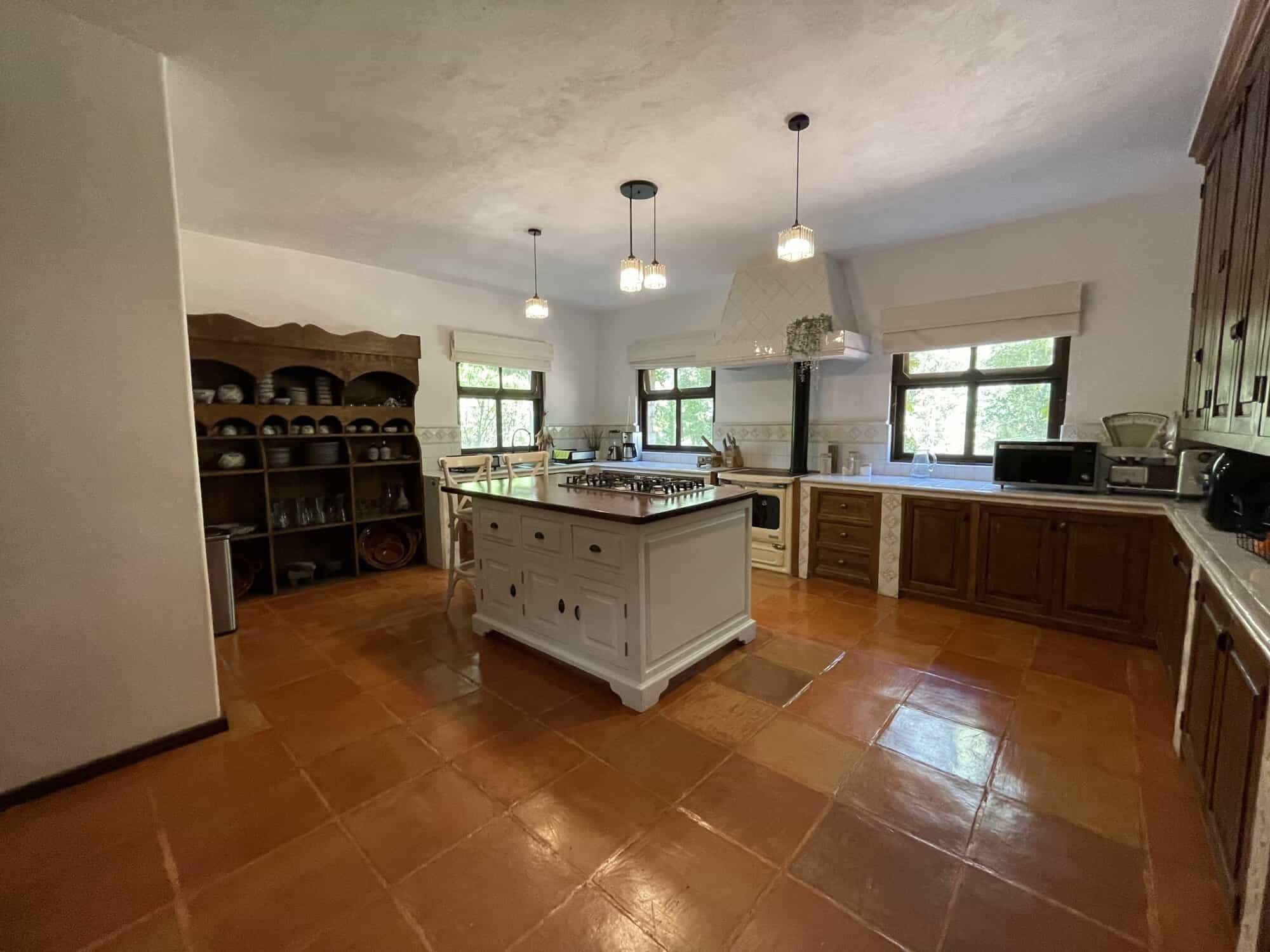 Spacious country kitchen with wooden cabinets, island, and large windows for natural light.