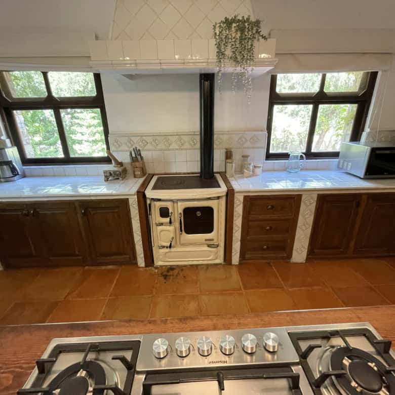 Bright kitchen with wooden cabinets and two large windows for natural light.