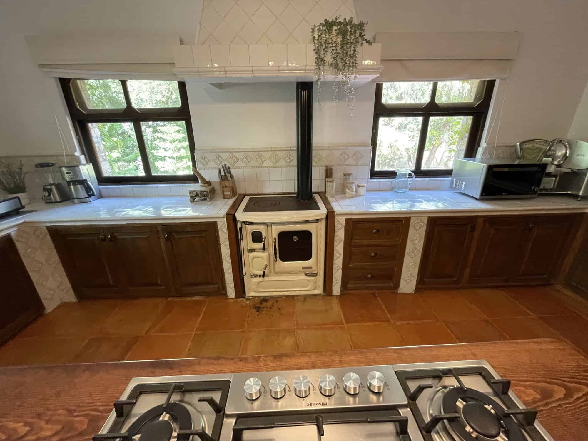 Bright kitchen with wooden cabinets and two large windows for natural light.