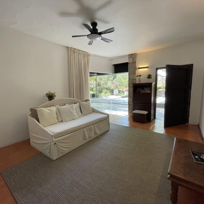 Living room with large window, ceiling fan, and cozy sofa for relaxing.