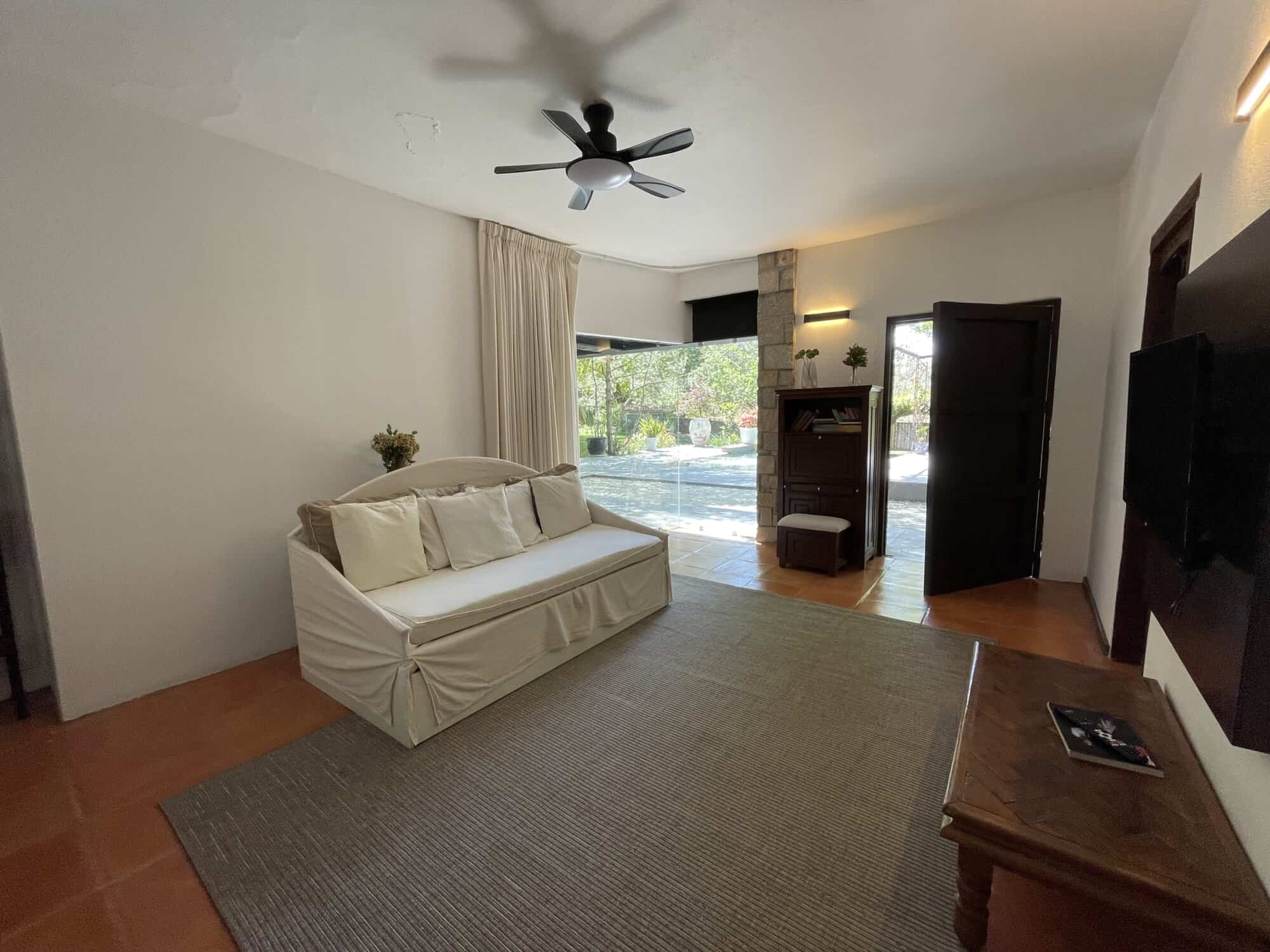 Living room with large window, ceiling fan, and cozy sofa for relaxing.