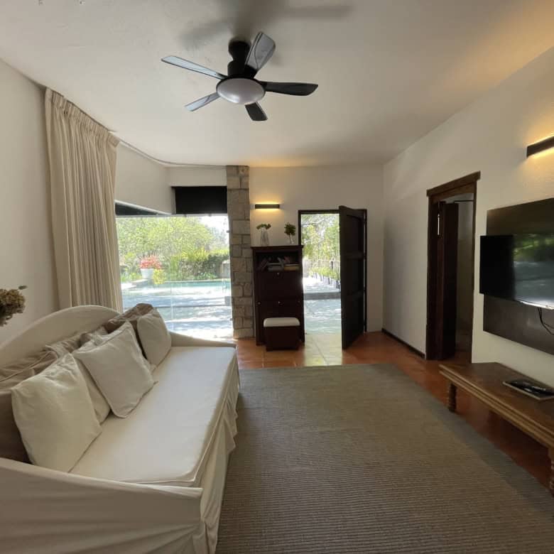 Spacious living room featuring a large window, ceiling fan, and contemporary furnishings for comfort.