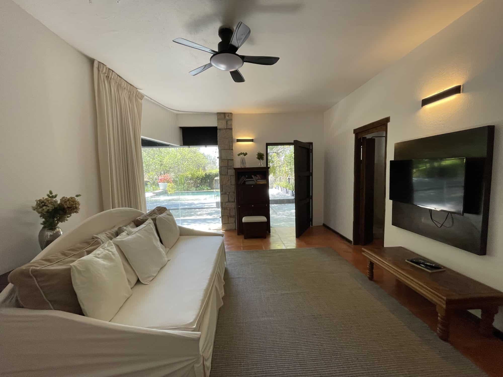Spacious living room featuring a large window, ceiling fan, and contemporary furnishings for comfort.