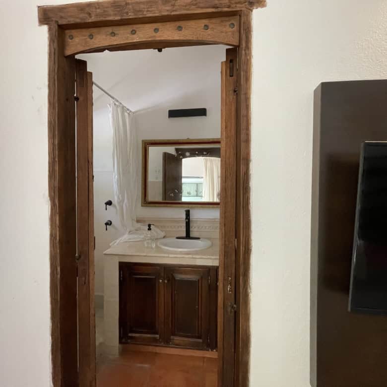 Rustic bathroom with wooden door frame and modern fixtures.