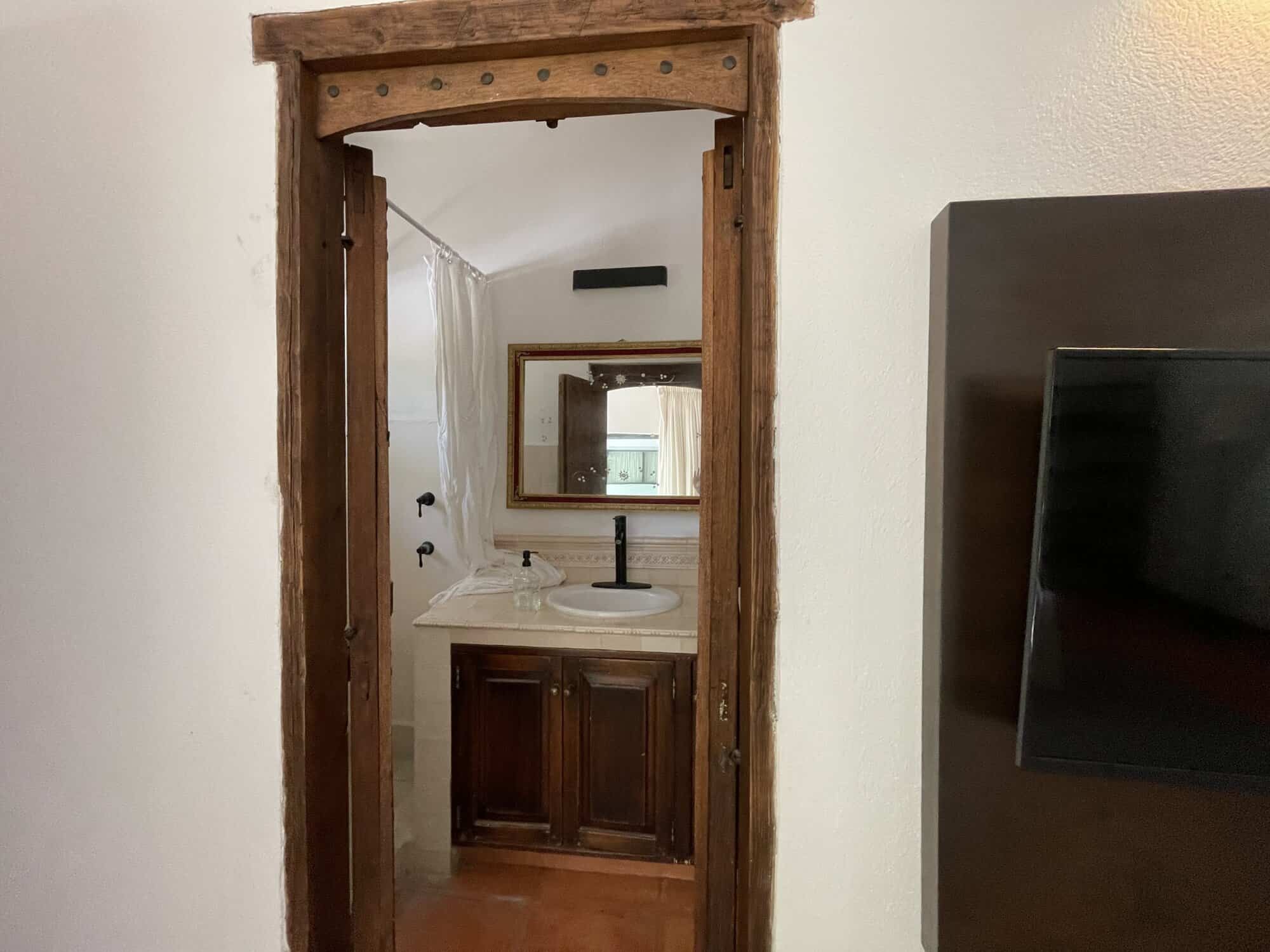 Rustic bathroom with wooden door frame and modern fixtures.