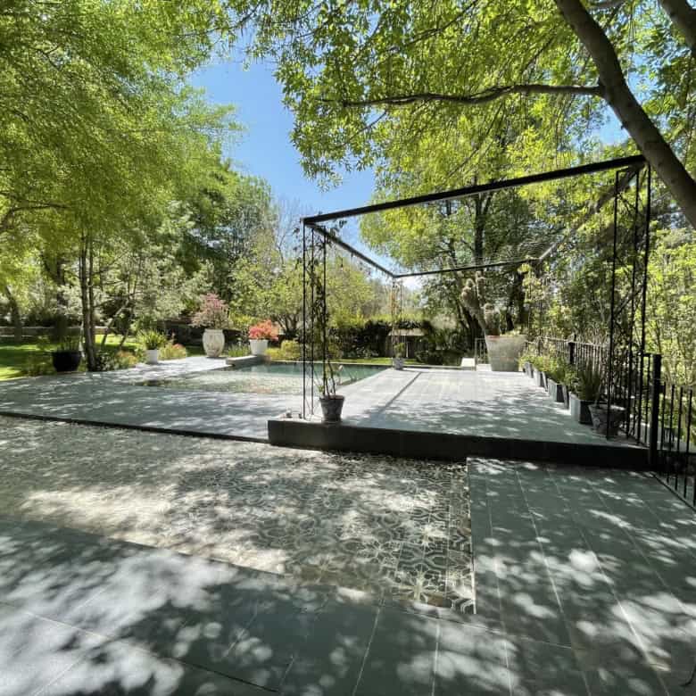 Luxury outdoor patio with lush greenery and shaded seating area.
