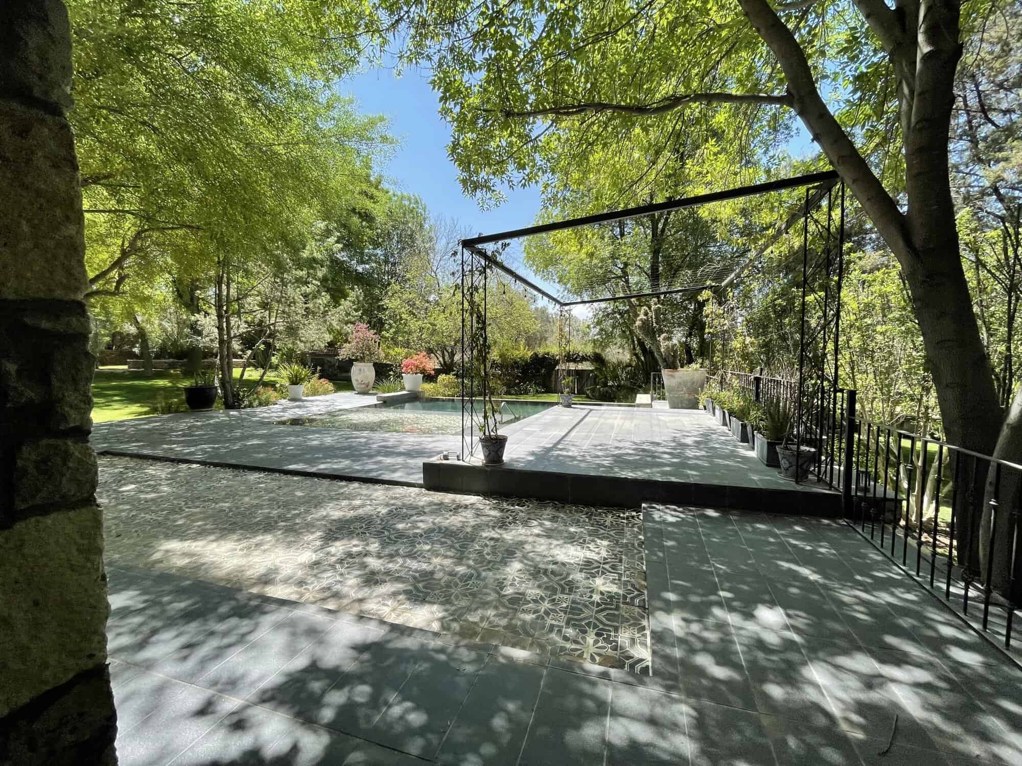 Luxury outdoor patio with lush greenery and shaded seating area.