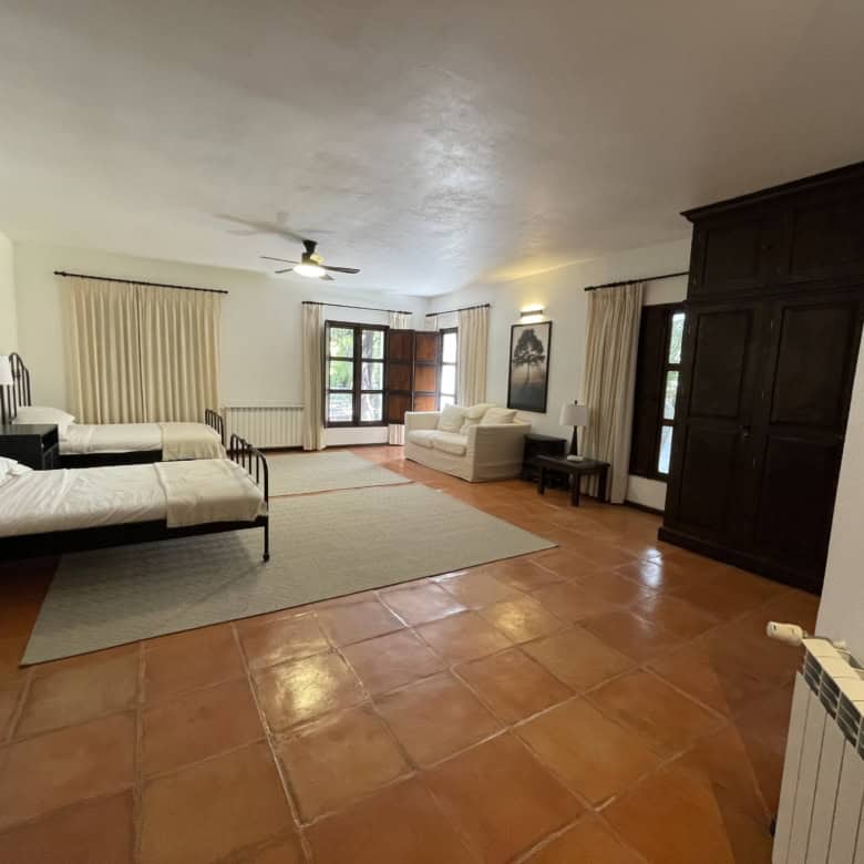 Bright bedroom with two beds, sitting area, and balcony access. Ideal for comfortable living in a sp.