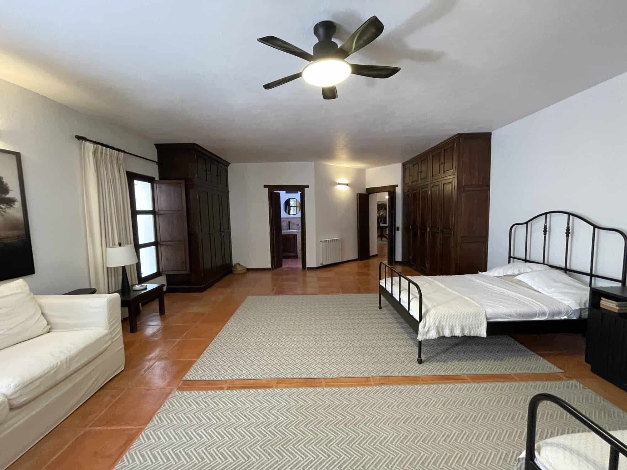 Bright and airy bedroom featuring a vintage iron bed and elegant wooden wardrobes. Perfect for comfo.