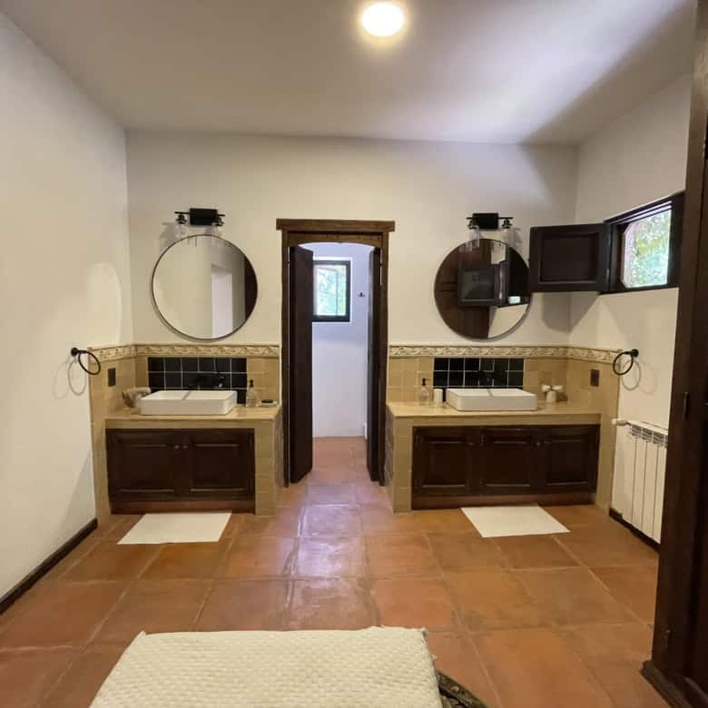 Bathroom with two sinks, round mirrors, and wooden cabinetry for a stylish look.