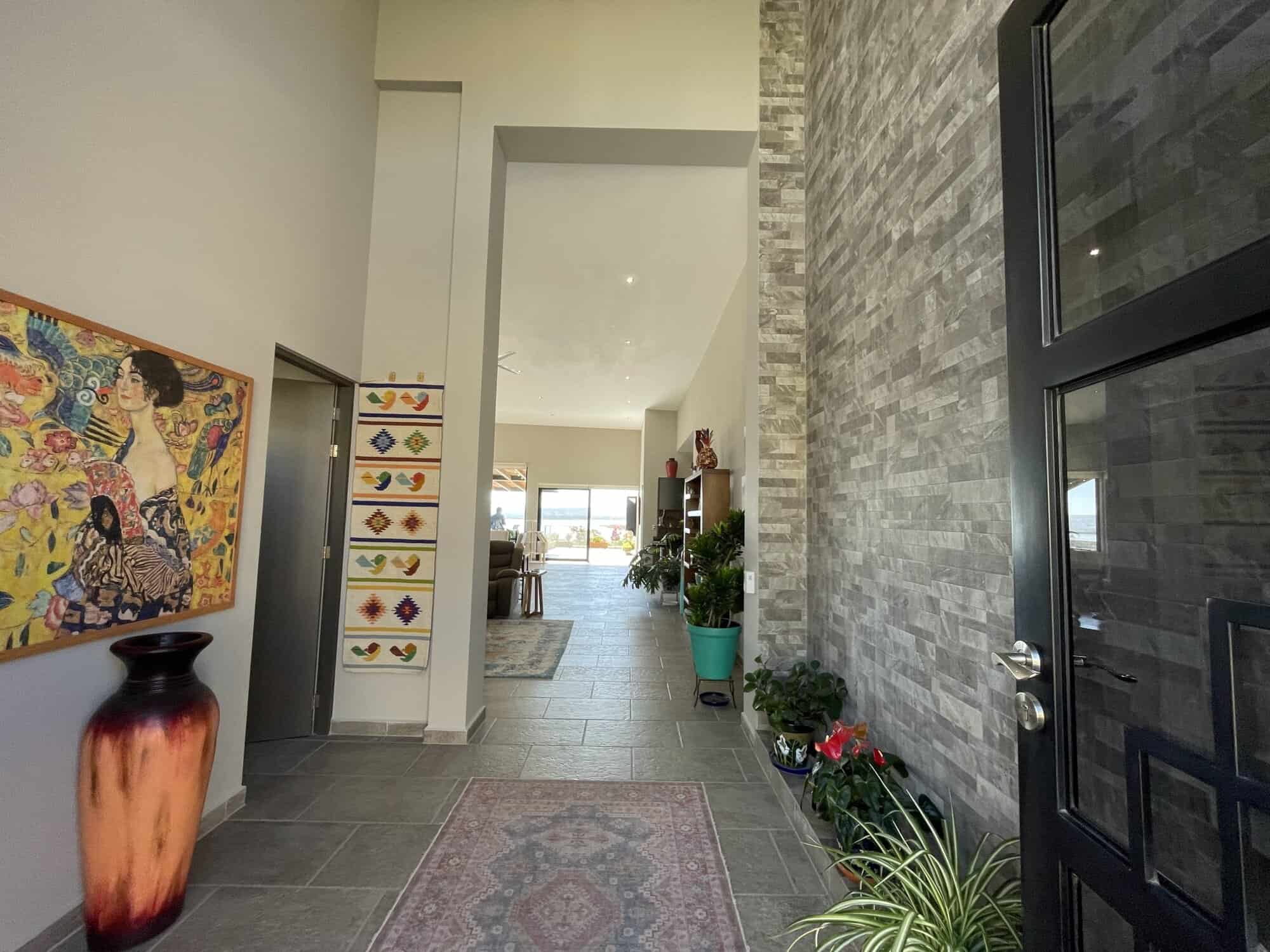 Spacious home entryway featuring contemporary decor, colorful artwork, and lush greenery.