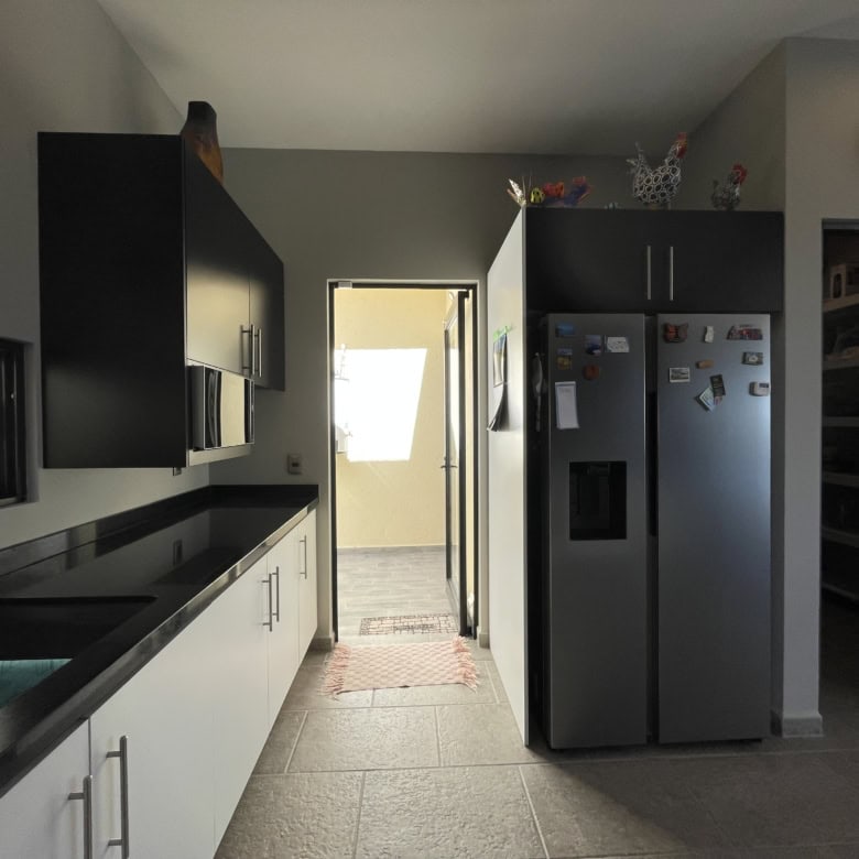 Bright kitchen with black and white cabinets, stainless steel fridge, and natural light.
