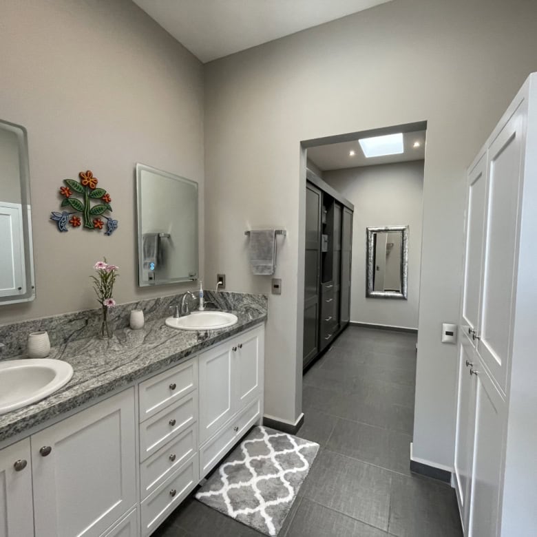 Modern bathroom with double sinks, granite countertops, and contemporary decor.