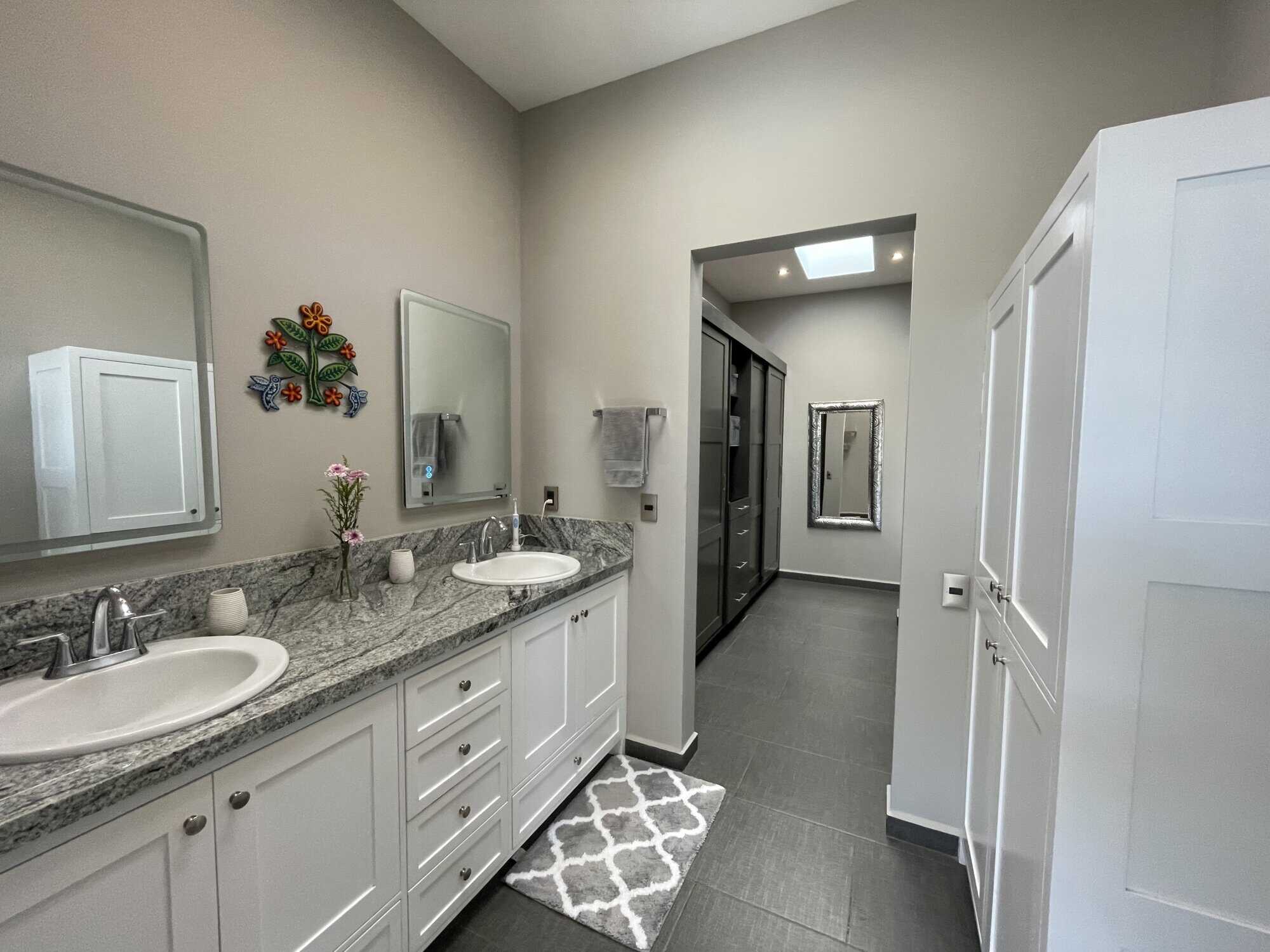 Modern bathroom with double sinks, granite countertops, and contemporary decor.