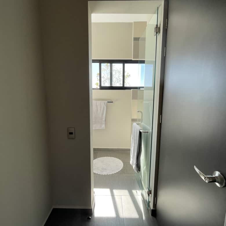Bathroom with glass shower and large window for natural lighting.