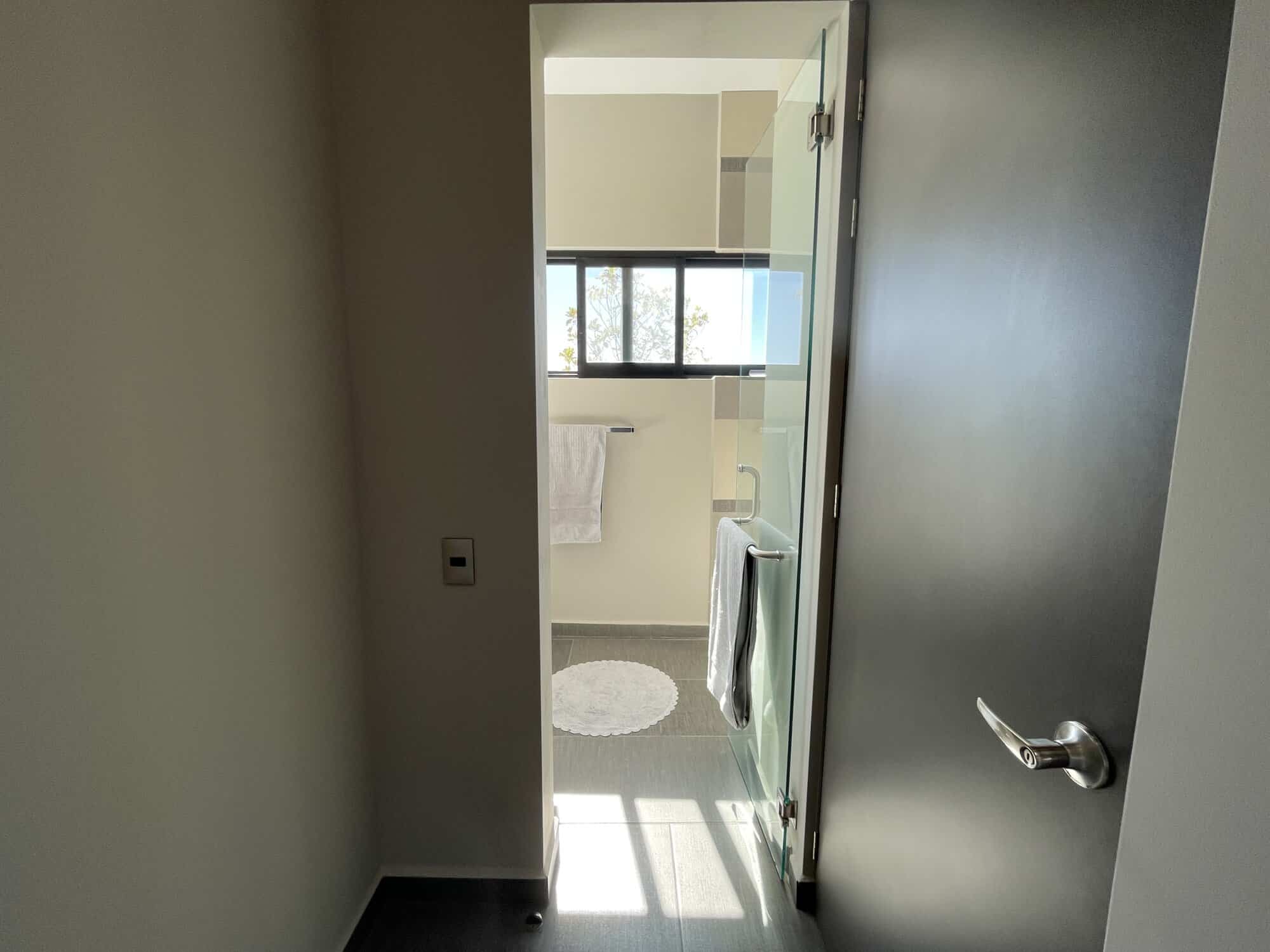 Bathroom with glass shower and large window for natural lighting.