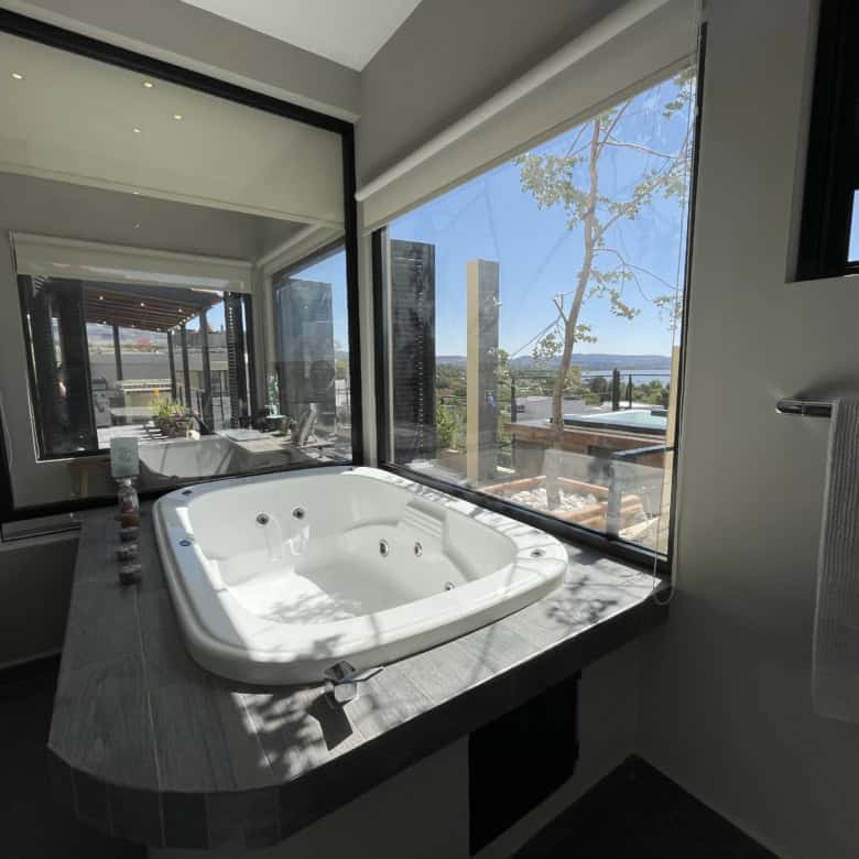 Indoor hot tub with large windows overlooking outdoor landscape.
