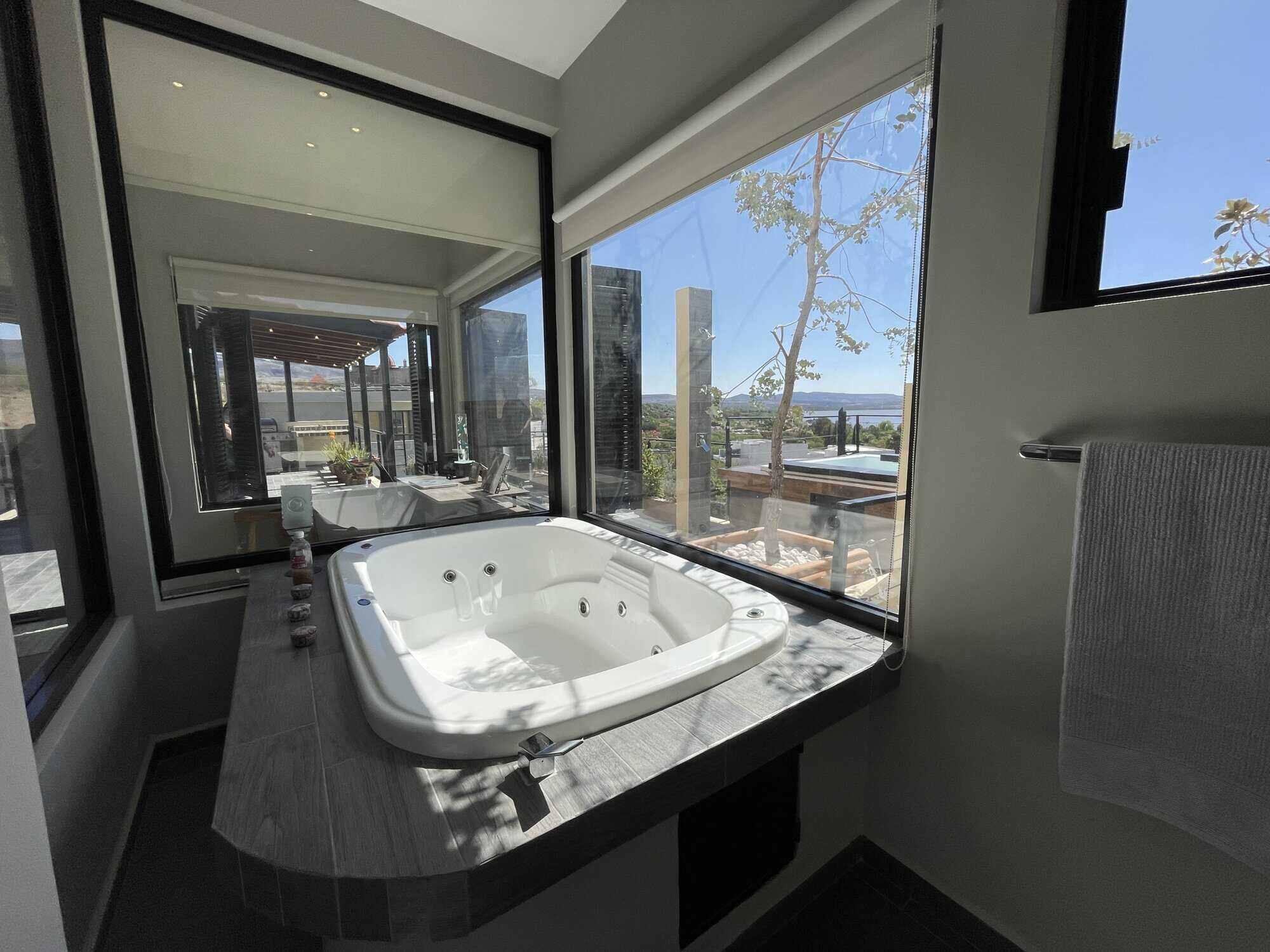 Indoor hot tub with large windows overlooking outdoor landscape.