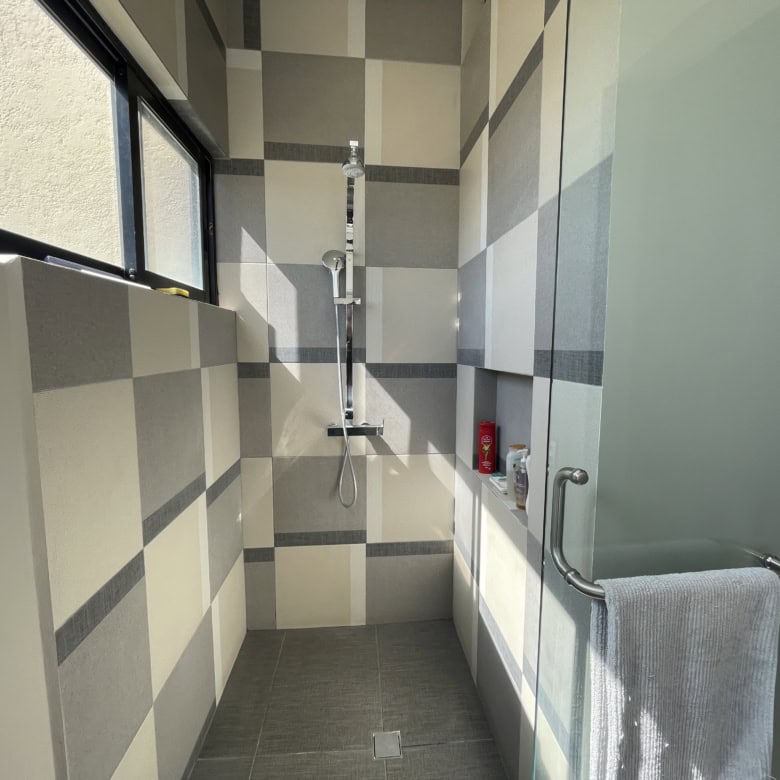Modern bathroom with shower, tiled walls, and a window for natural light.