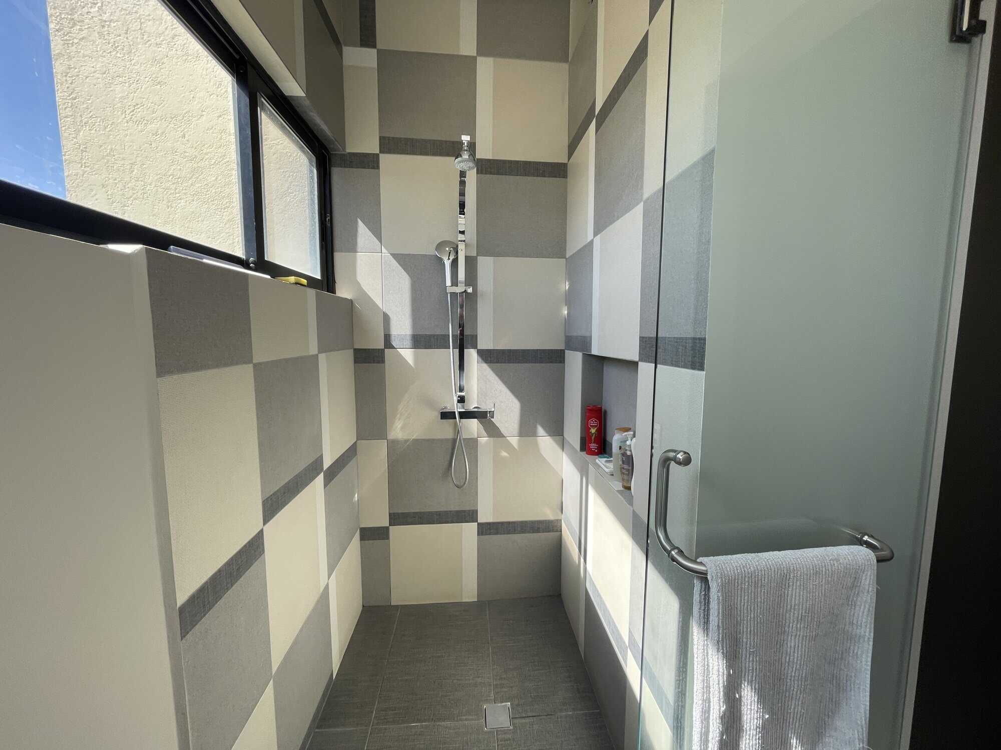 Modern bathroom with shower, tiled walls, and a window for natural light.