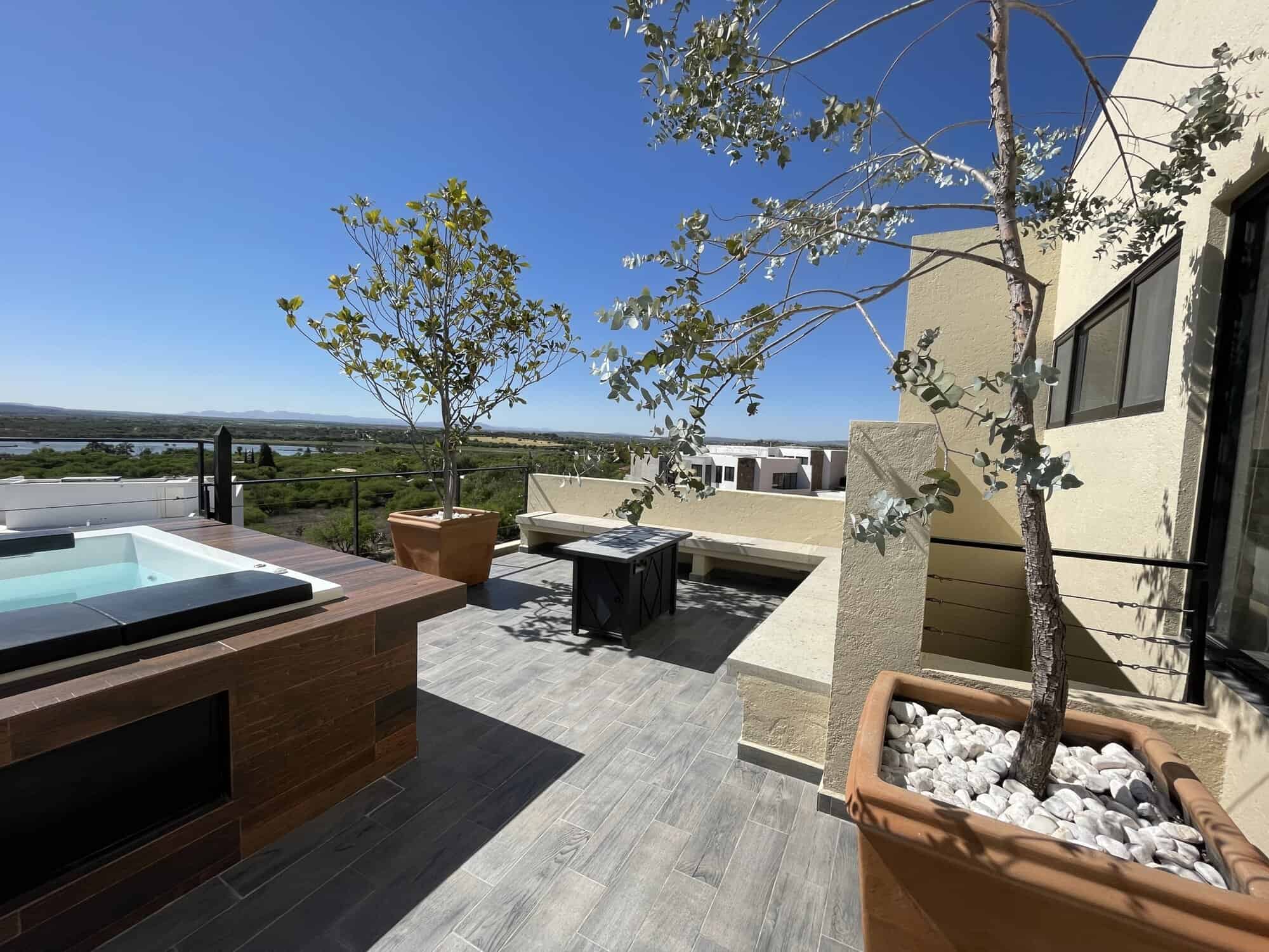 Rooftop terrace featuring modern outdoor furniture, potted trees, and scenic cityscape views under a.