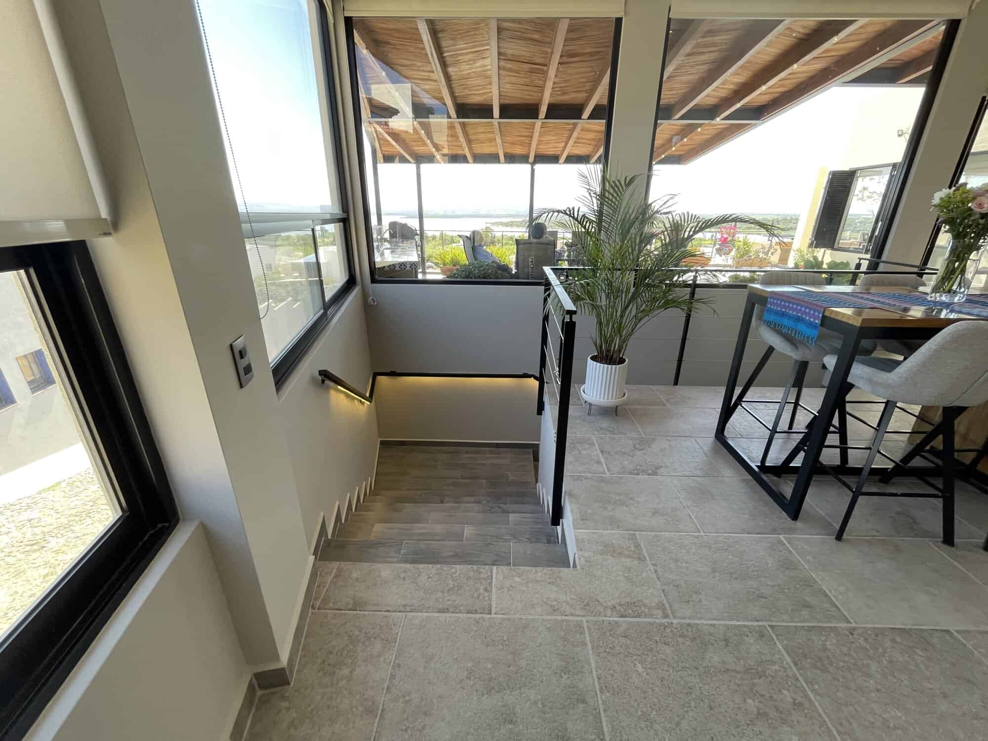 Balcony with large glass windows, outdoor seating, and scenic views, perfect for relaxing and enjoyi.