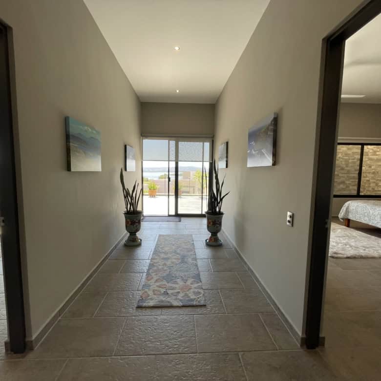 Bright hallway leading to balcony with sea views and potted plants.