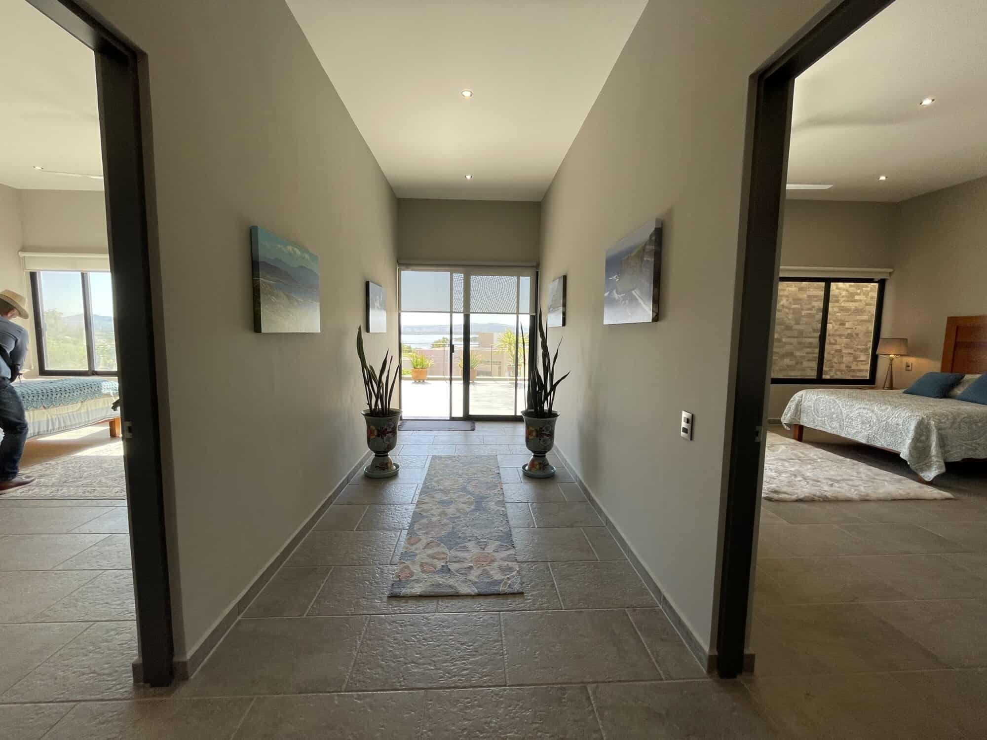 Bright hallway leading to balcony with sea views and potted plants.