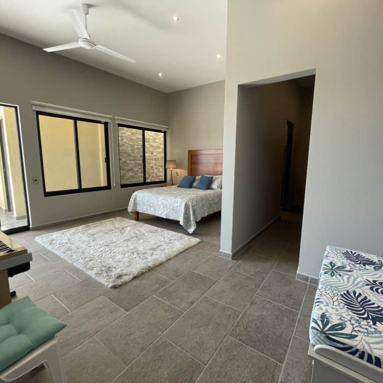 Spacious bedroom featuring large windows, balcony access, and contemporary decor for comfortable liv.