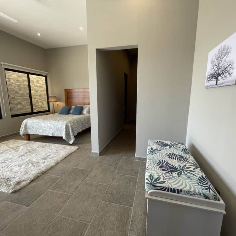 Spacious bedroom featuring large windows, neutral tones, and contemporary furnishings for a comforta.