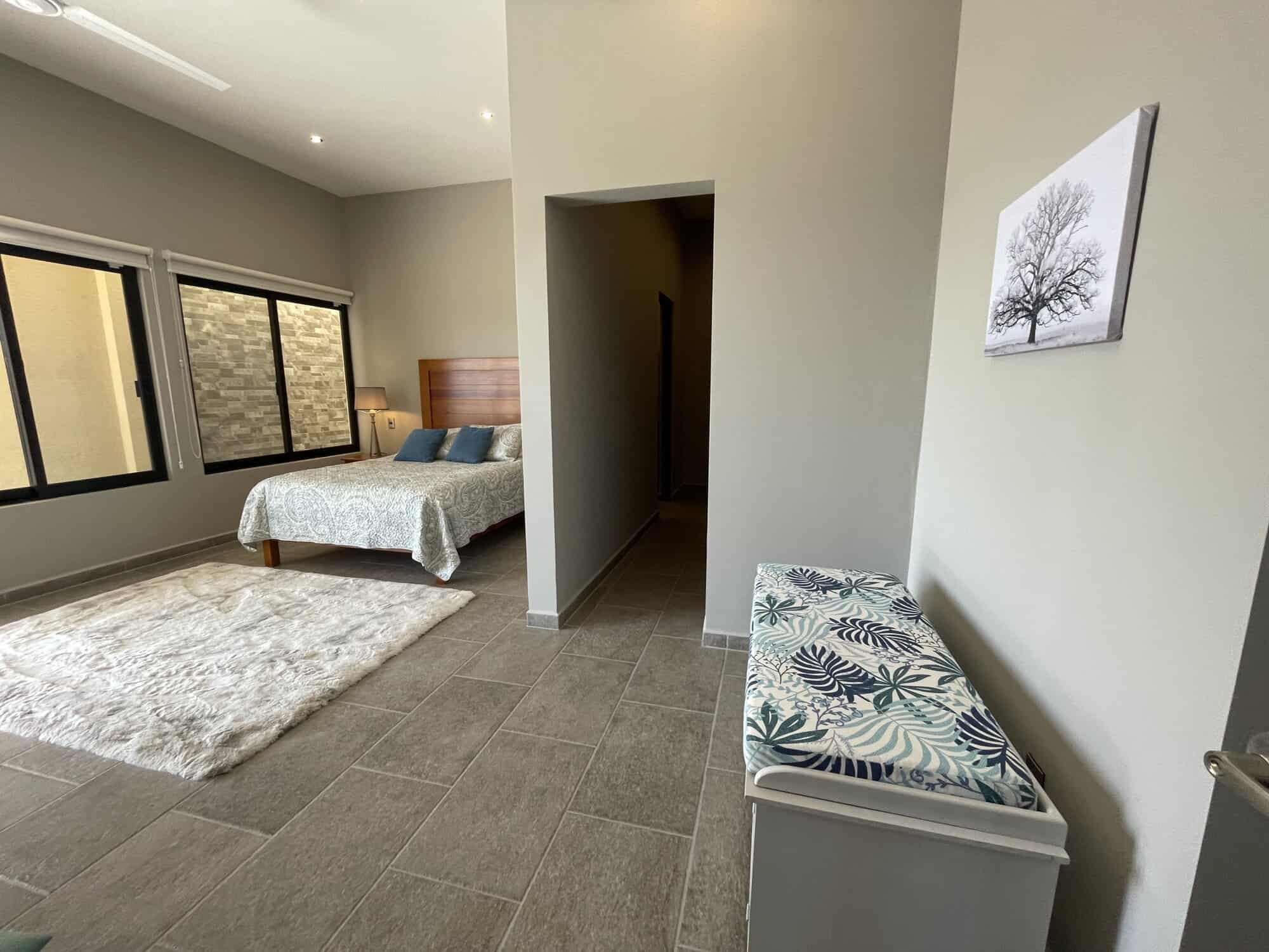 Spacious bedroom featuring large windows, neutral tones, and contemporary furnishings for a comforta.