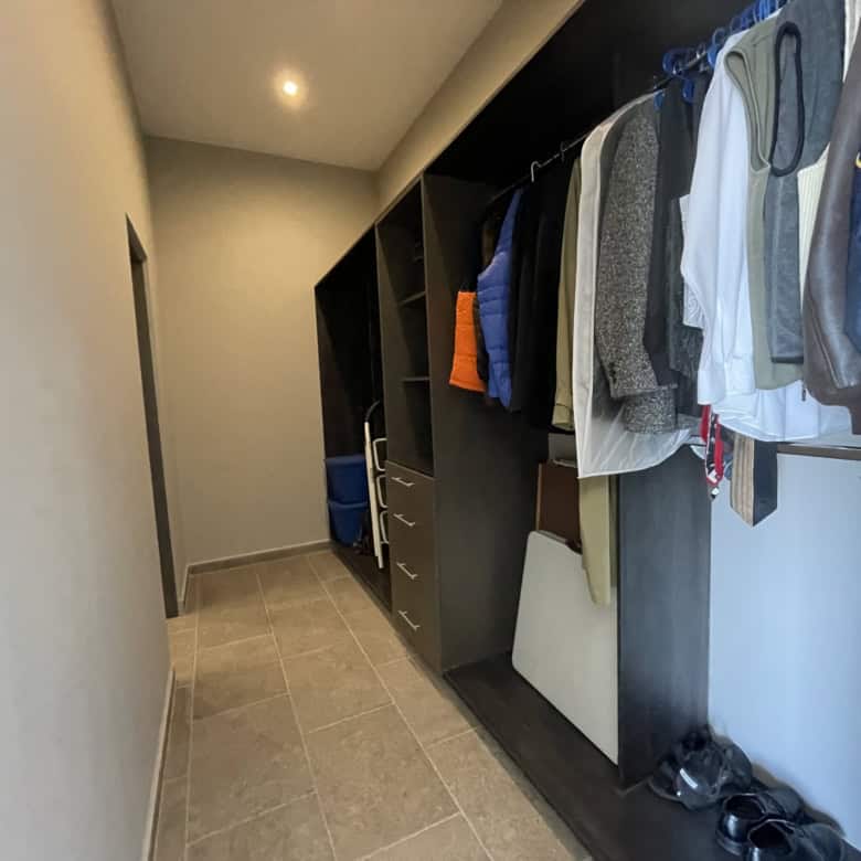 Spacious walk-in closet with hanging clothes and organized storage shelves.
