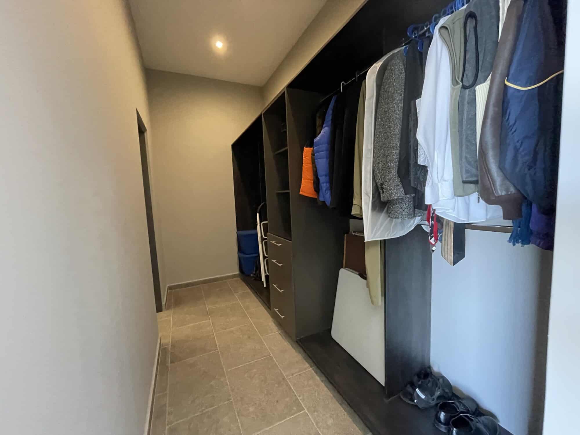 Spacious walk-in closet with hanging clothes and organized storage shelves.