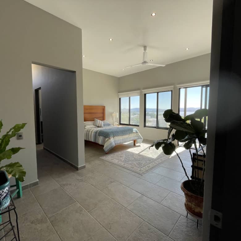 Bright bedroom with large windows overlooking cityscape and mountains.