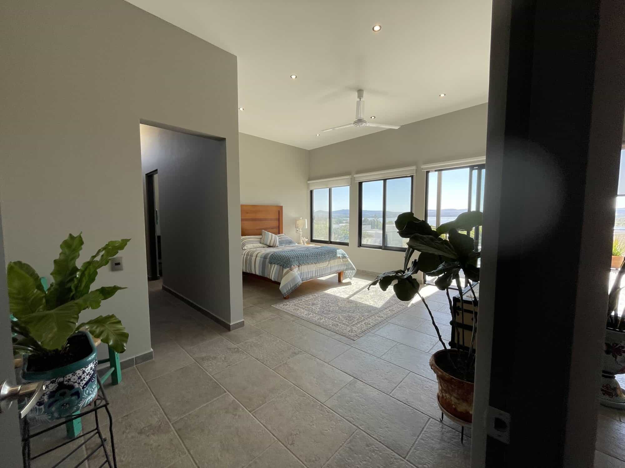 Bright bedroom with large windows overlooking cityscape and mountains.