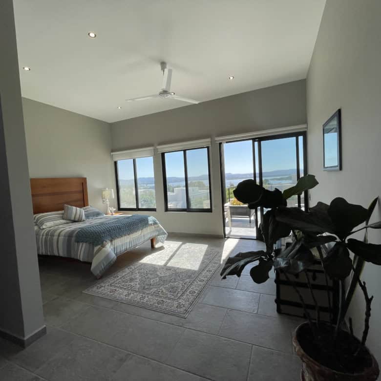 Modern bedroom with large windows offering city views and natural light.