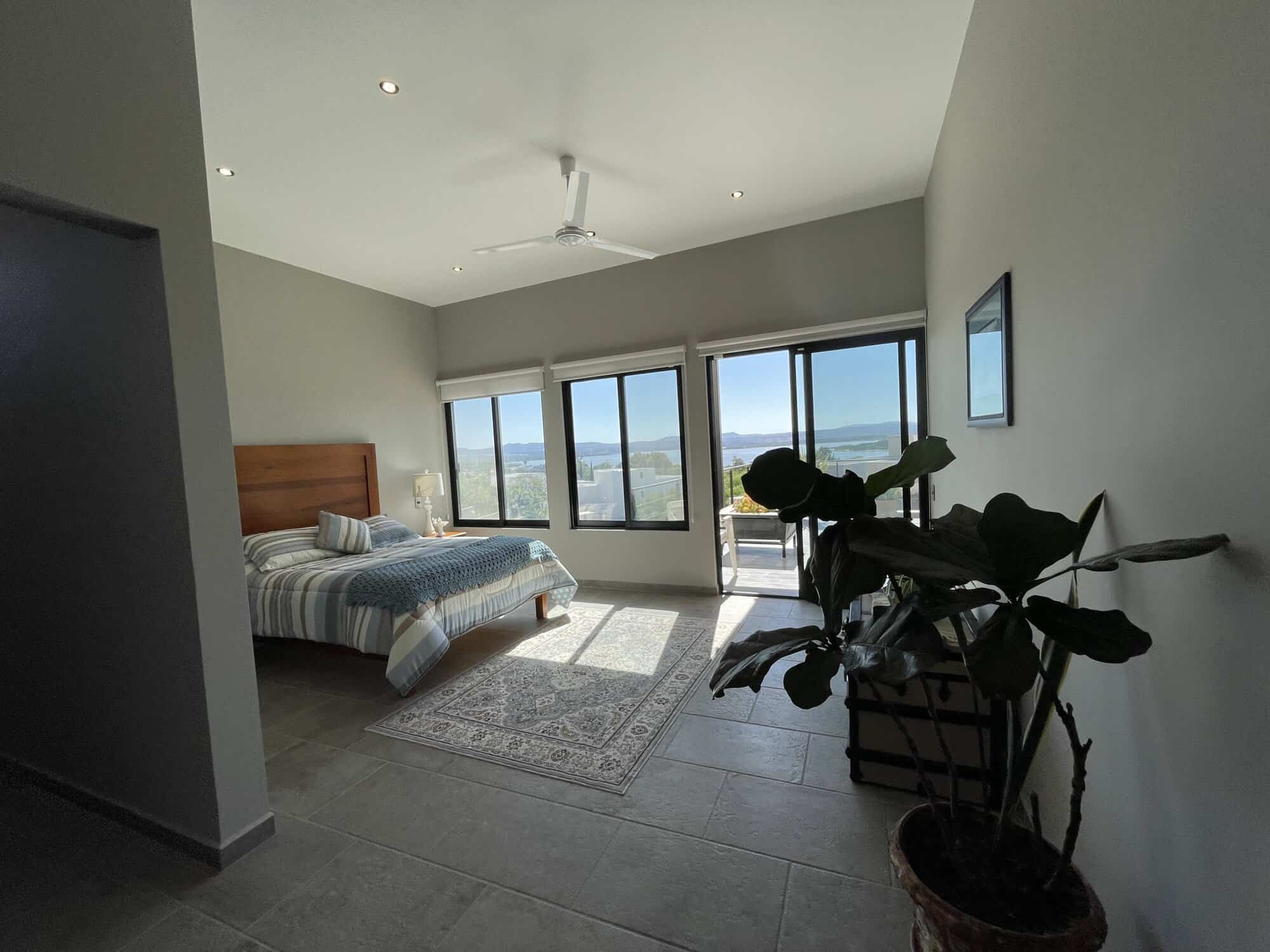 Modern bedroom with large windows offering city views and natural light.