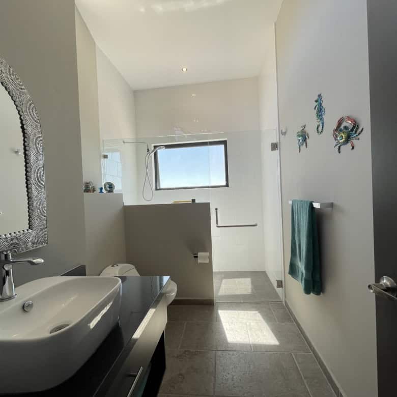 Bright bathroom featuring a large window with ocean view and stylish fish decorations on the wall.