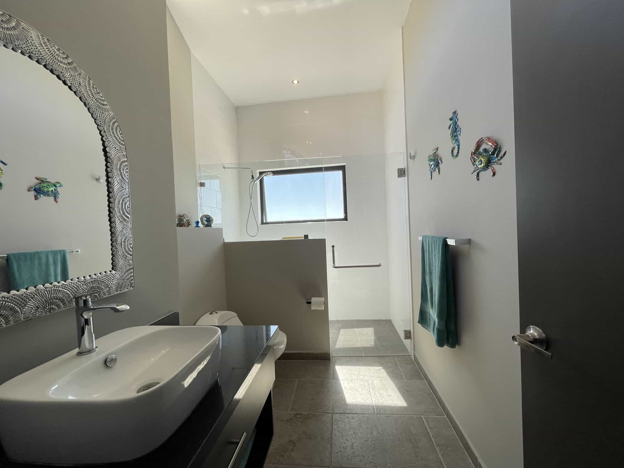Bright bathroom featuring a large window with ocean view and stylish fish decorations on the wall.