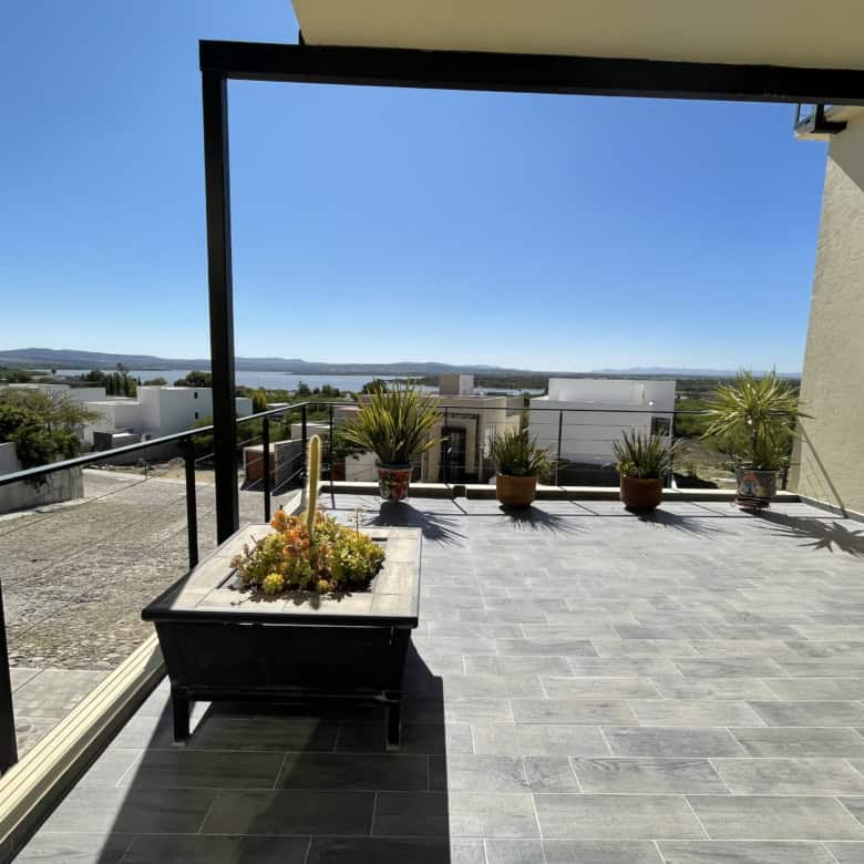 Balcony with water views, potted plants, and modern flooring.