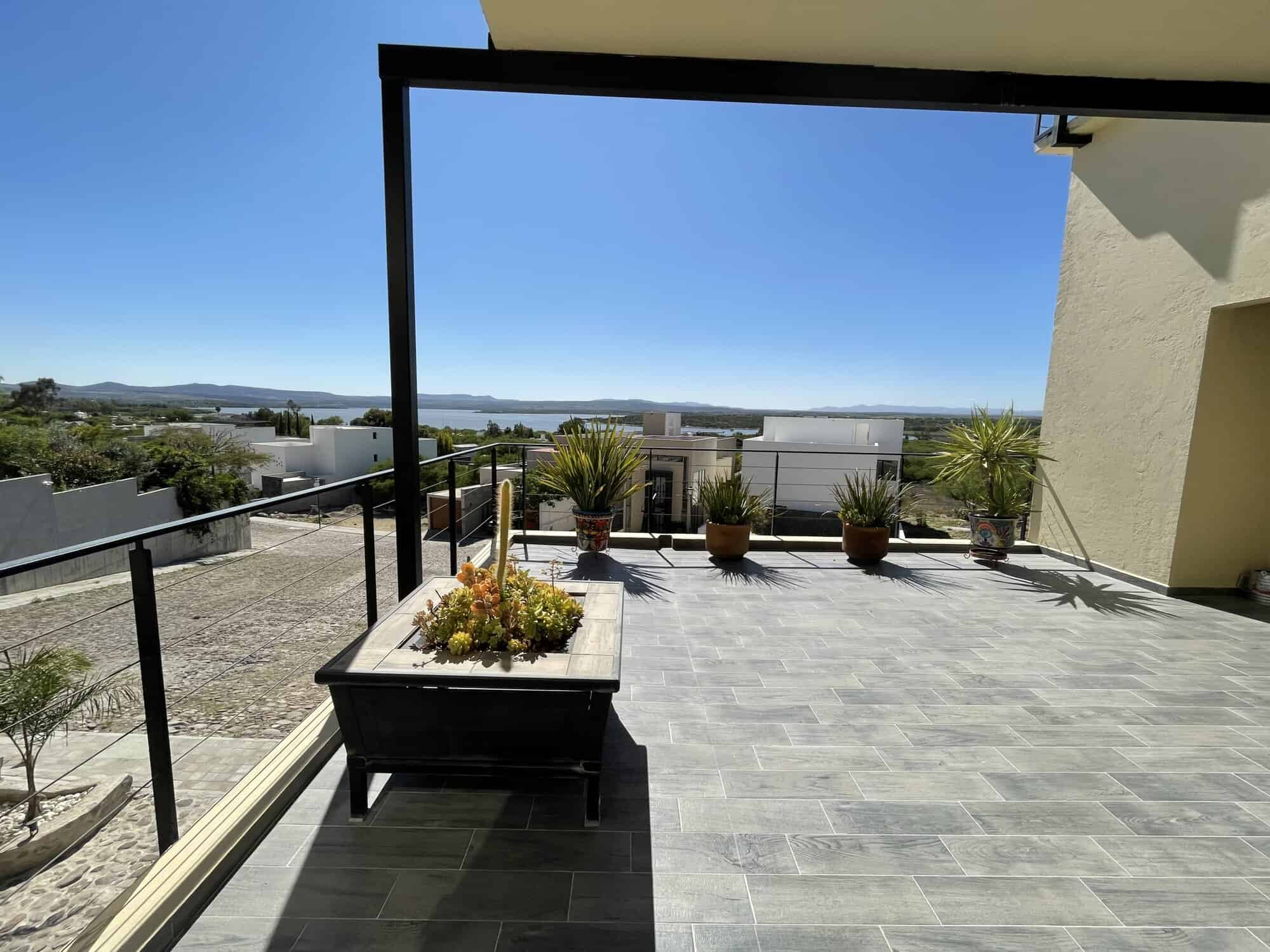 Balcony with water views, potted plants, and modern flooring.