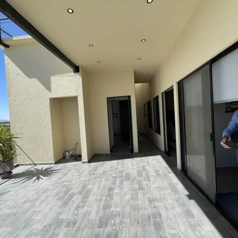 Spacious balcony featuring glass sliding doors, overlooking a beautiful landscape with clear blue sk.