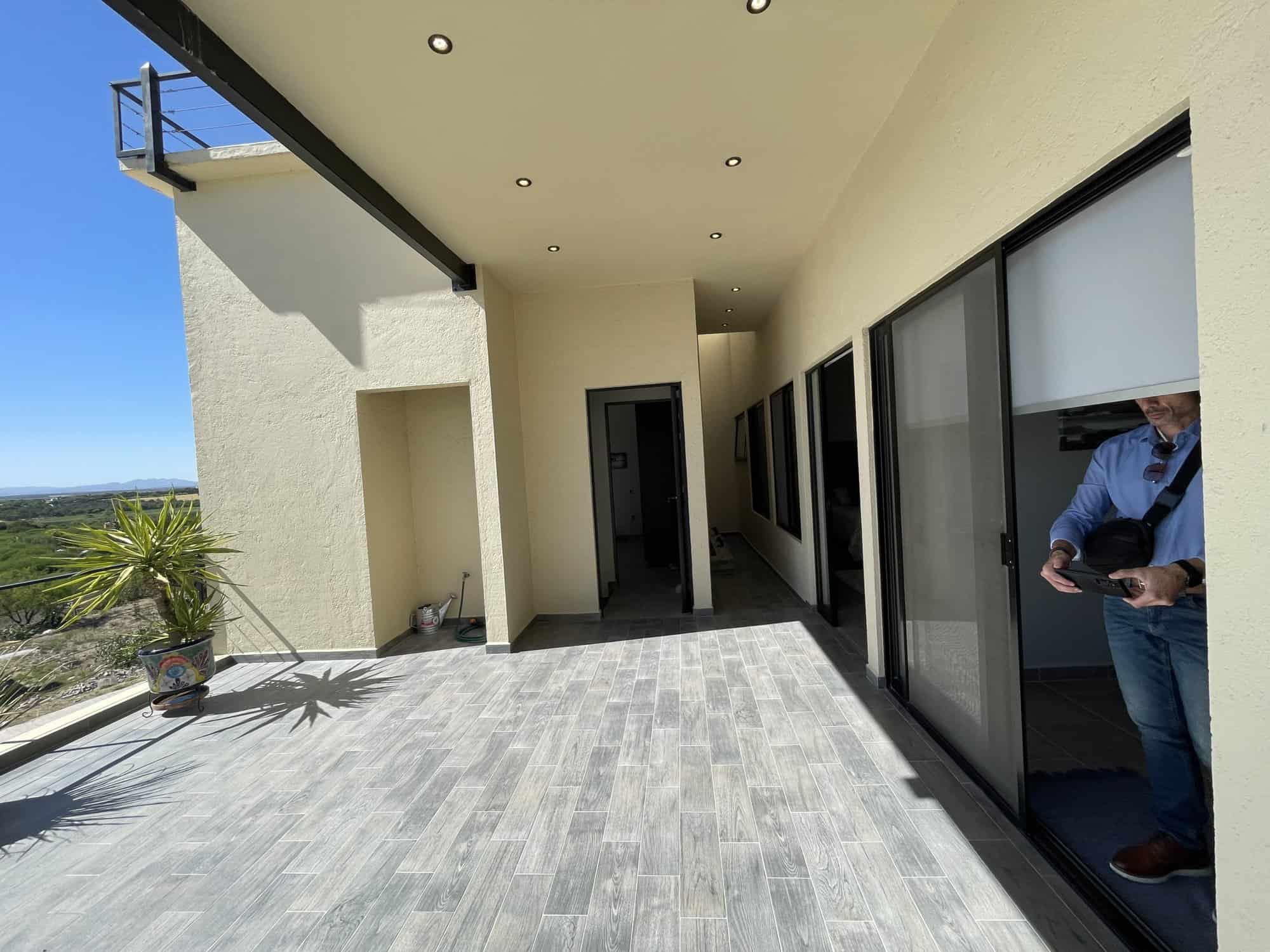 Spacious balcony featuring glass sliding doors, overlooking a beautiful landscape with clear blue sk.