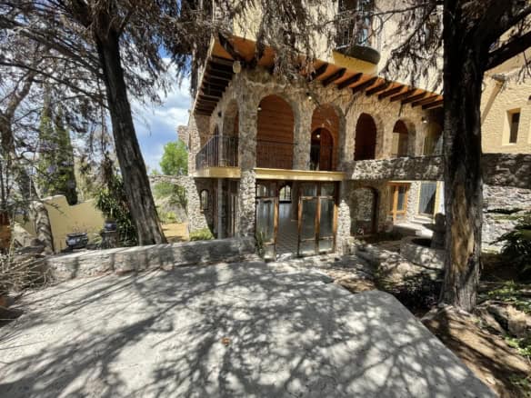 Luxury stone house with wooden accents in a wooded area.