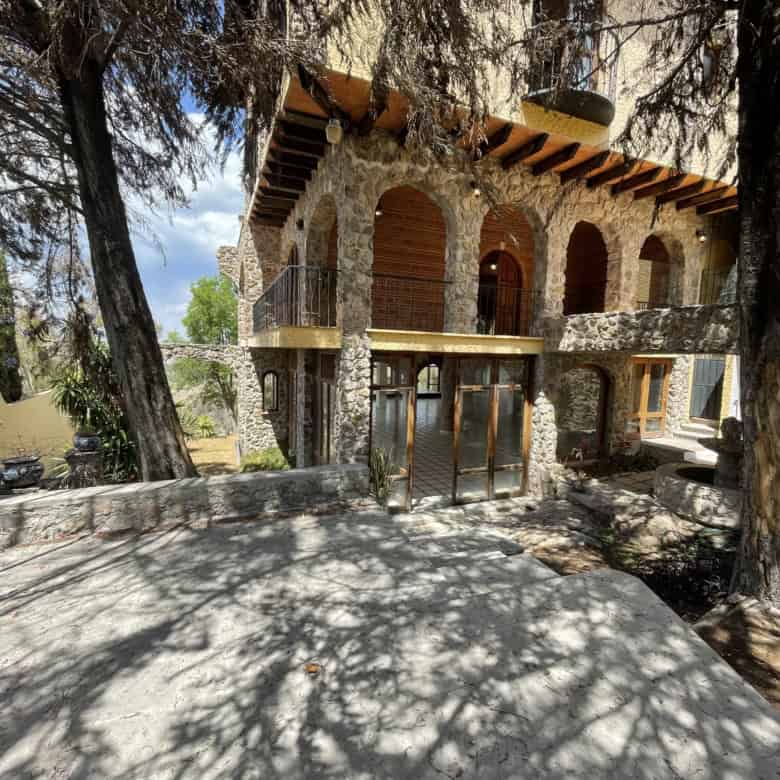 Luxury stone house with wooden accents in a wooded area.