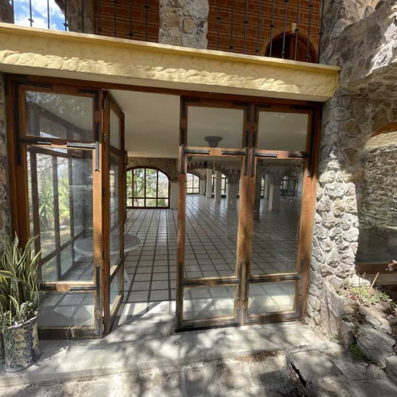 Luxury stone house with large glass doors and garden view.