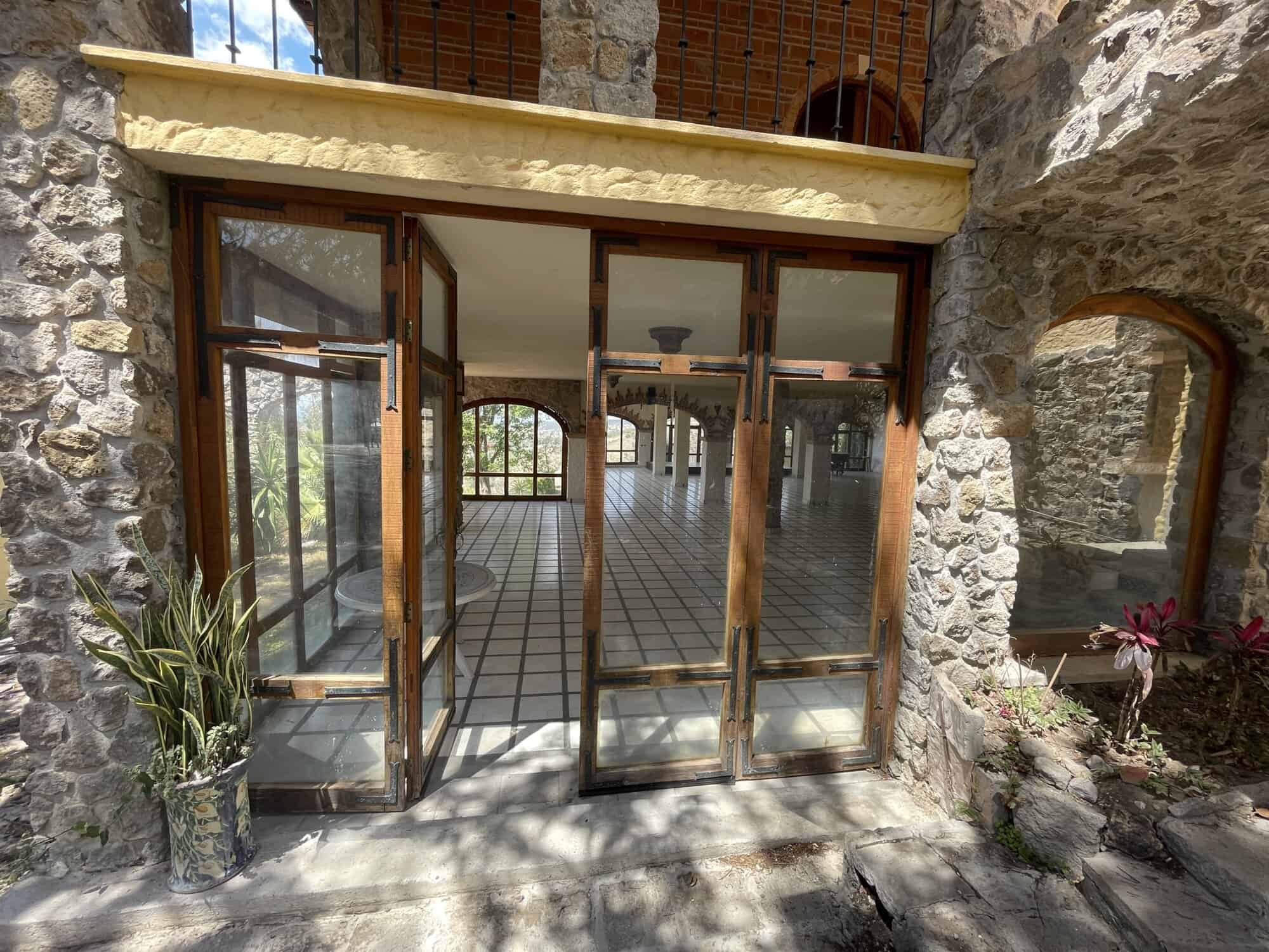 Luxury stone house with large glass doors and garden view.