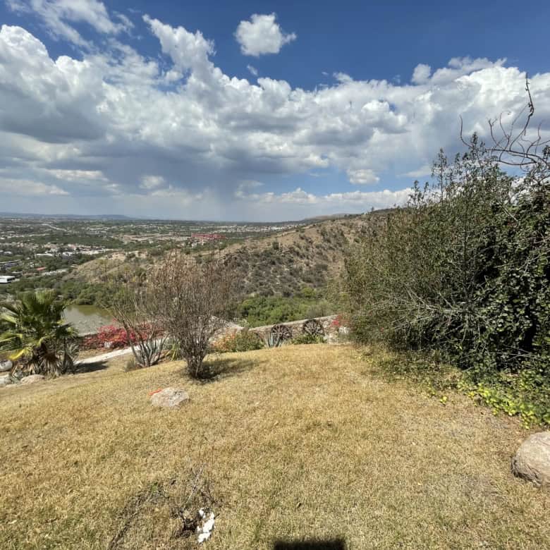 Beautiful hillside landscape overlooking a city with lush greenery and open sky.