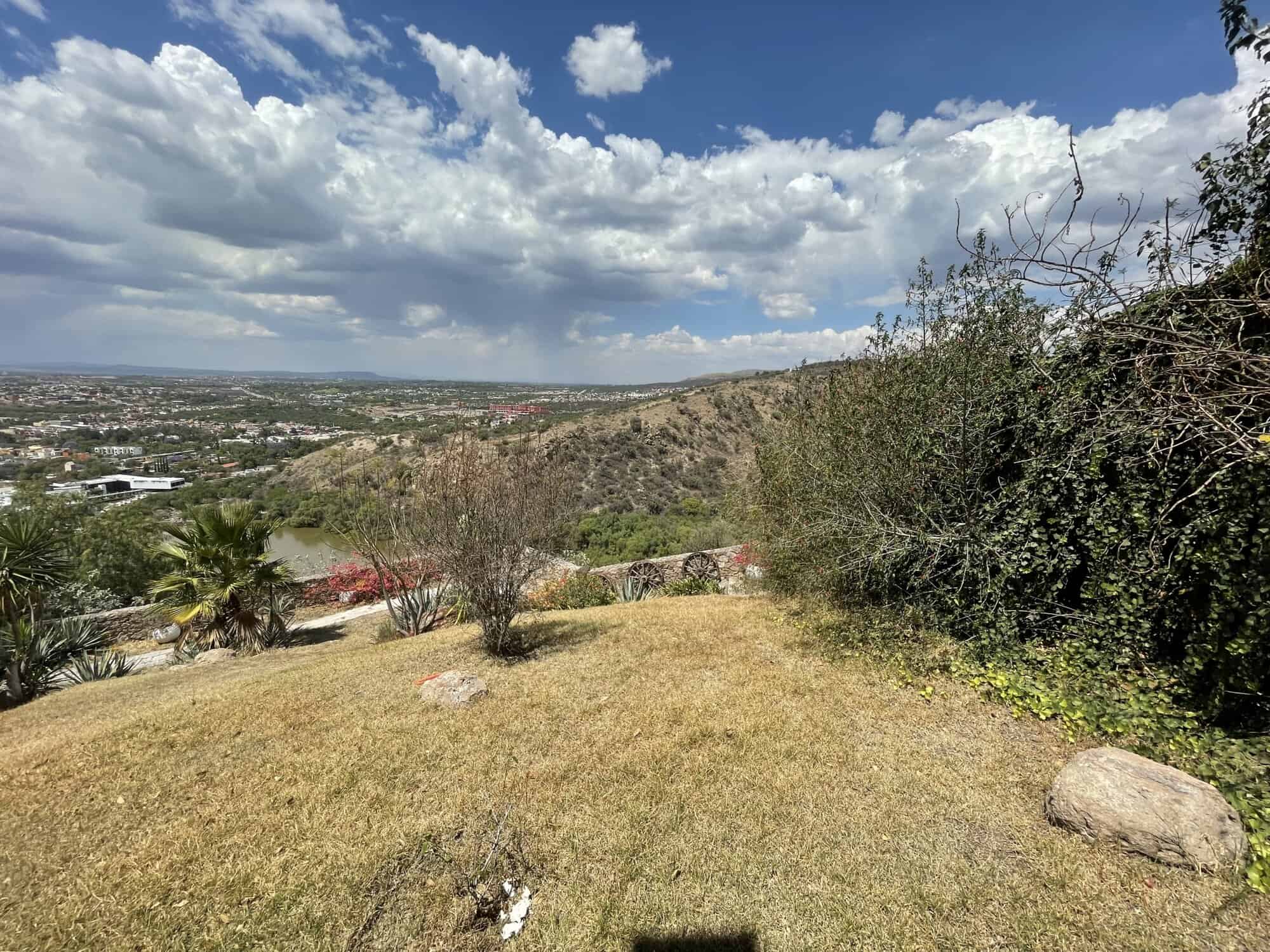 Beautiful hillside landscape overlooking a city with lush greenery and open sky.